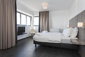 Relax in a spacious room with a large bed, flat-screen TV, and modern wardrobe.