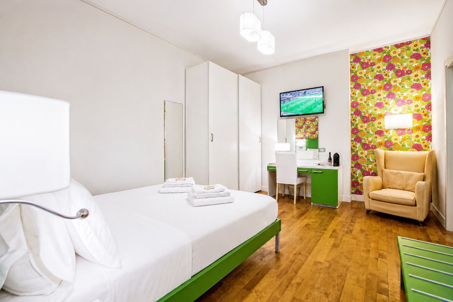A hotel room with a bed, a desk, a chair, and a television.