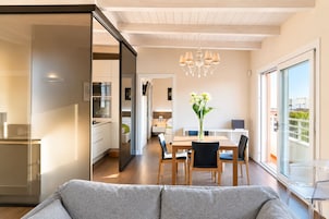 Un interior moderno con zona de comedor, cocina y un amplio ventanal corredera a un balcón.