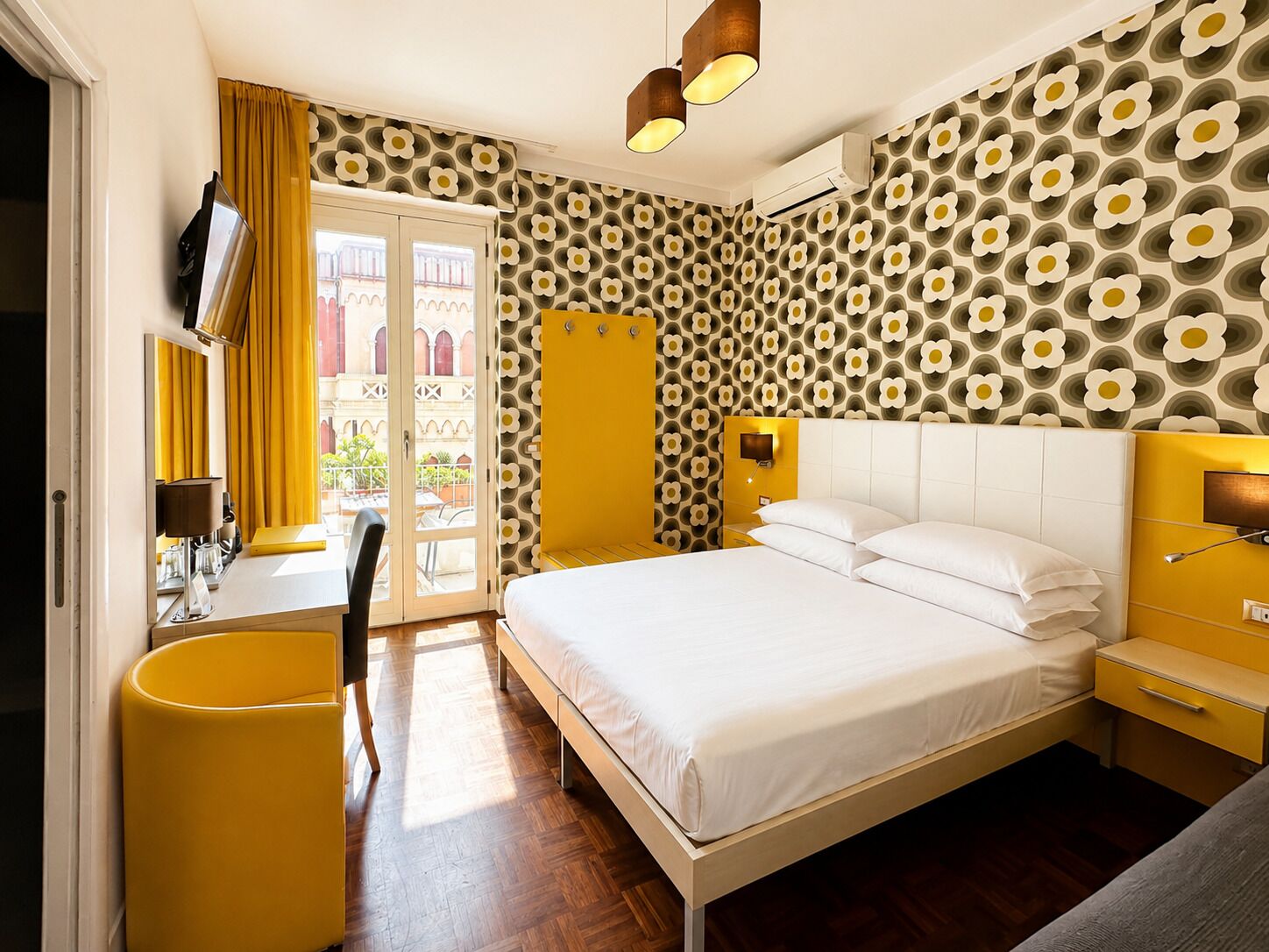 Una habitación de hotel con cama, mesita de noche y escritorio con silla.