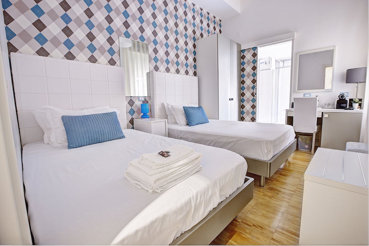 A hotel room with two beds, a desk, and a chair.