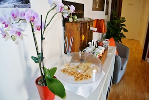 Una habitación con una mesa de comedor lista para una comida, una orquídea en maceta y un mueble de madera con diversos objetos.