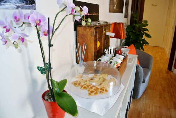 A room with a dining table set for a meal, a potted orchid, and a wooden cabinet with various items. - B&B Pellicano Guest House (Reggio Calabria)