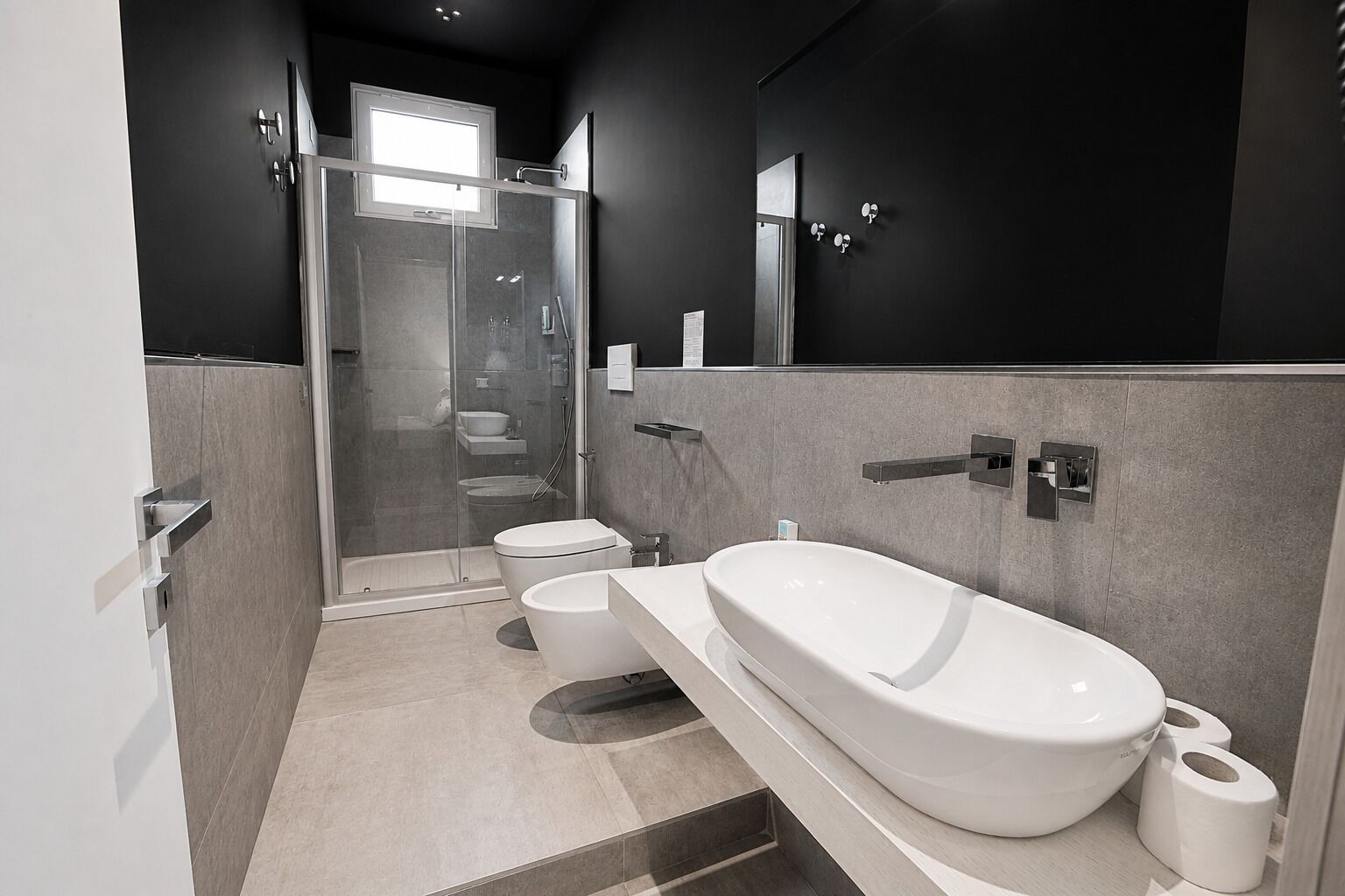 Een moderne badkamer met een douchecabine van glas, een toilet, een wastafel en een bad.