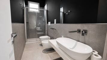 Une salle de bain moderne avec une douche à parois de verre, des toilettes, un lavabo et une baignoire.