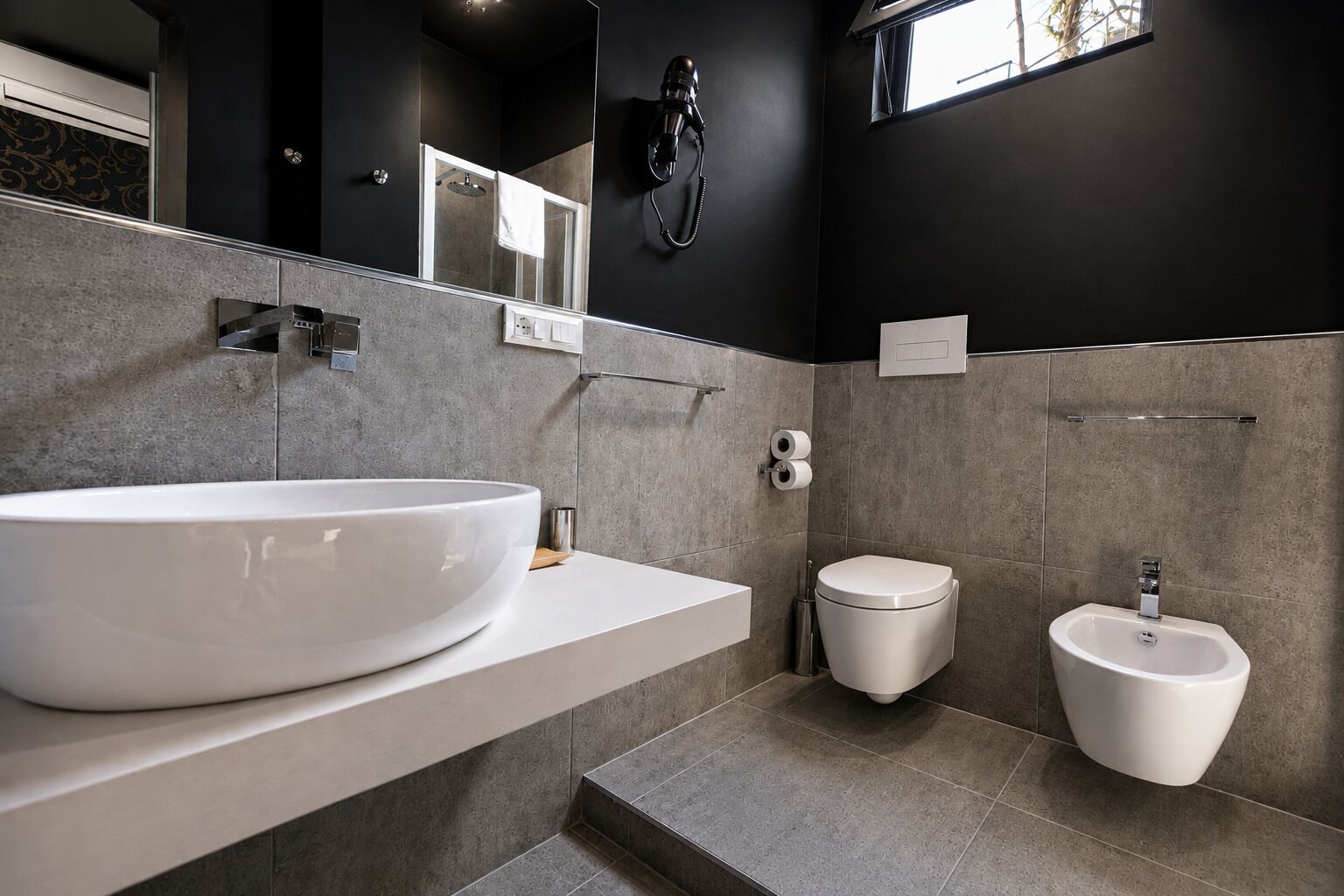 Un baño moderno con un lavamanos grande blanco, un inodoro y un bidé.