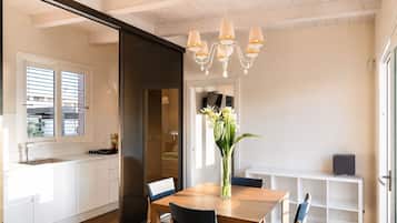 A modern kitchen with a dining area, a chandelier, and a view through a sliding door.