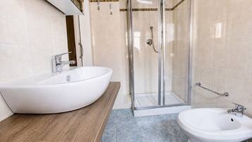 Ein Badezimmer mit einem großzügigen Vessel-Waschbecken, einem separaten Standwaschbecken, einer Duschkabine und einem Bidet.