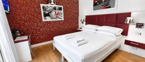 A hotel room with a bed, bedside tables, a desk, and a chair.