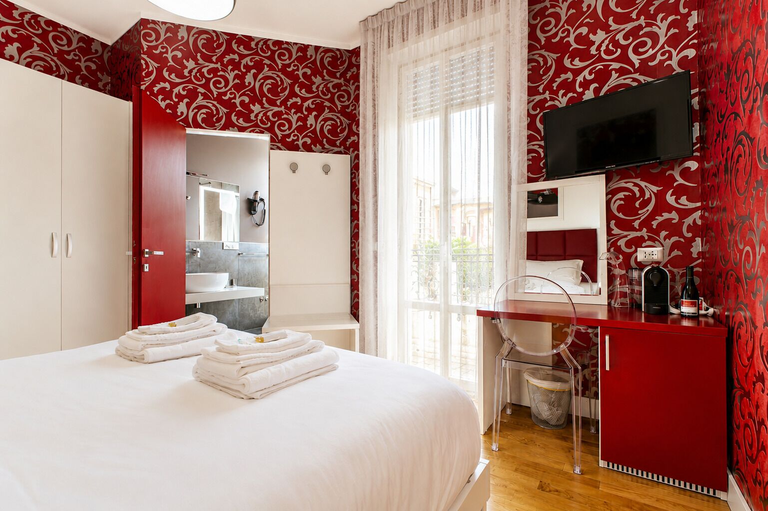 A hotel room with a bed, a desk, a TV, and a bathroom.