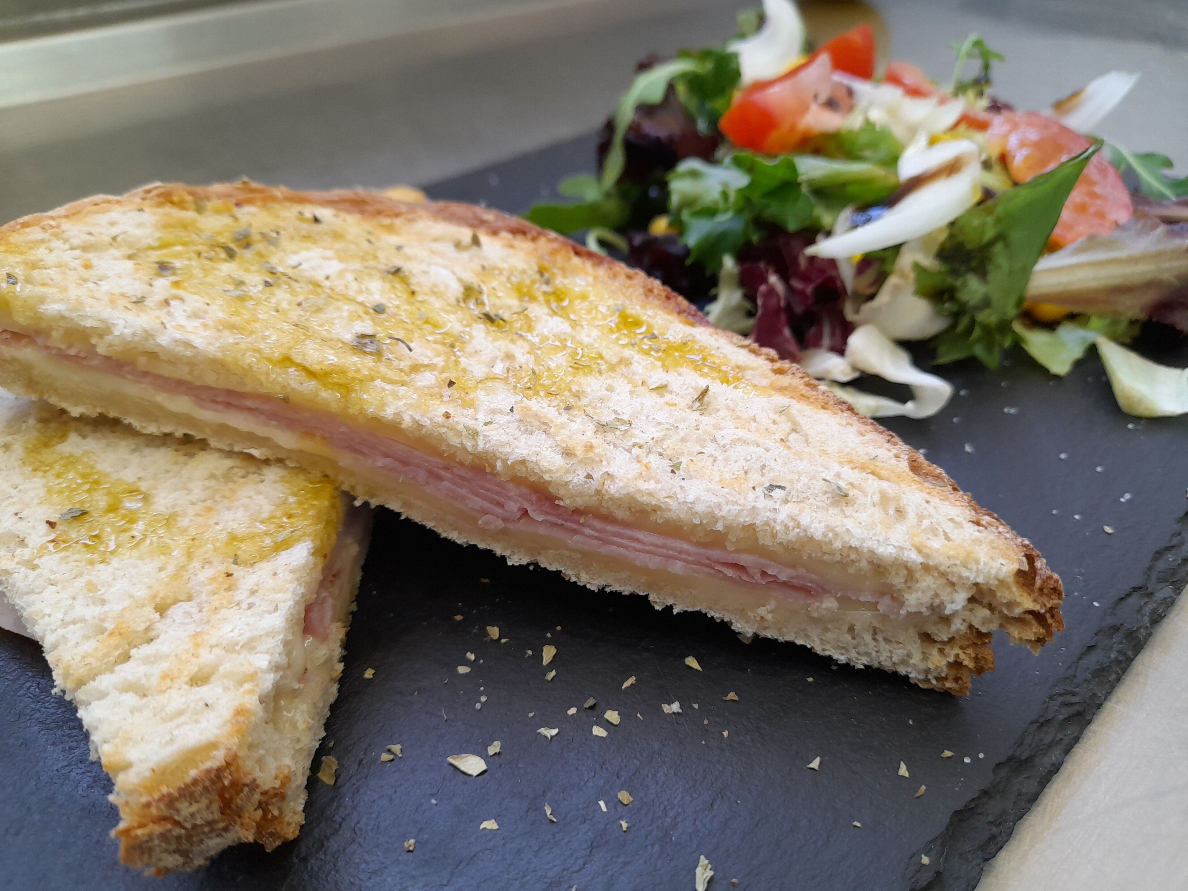 A sandwich on a slate plate with a side salad.