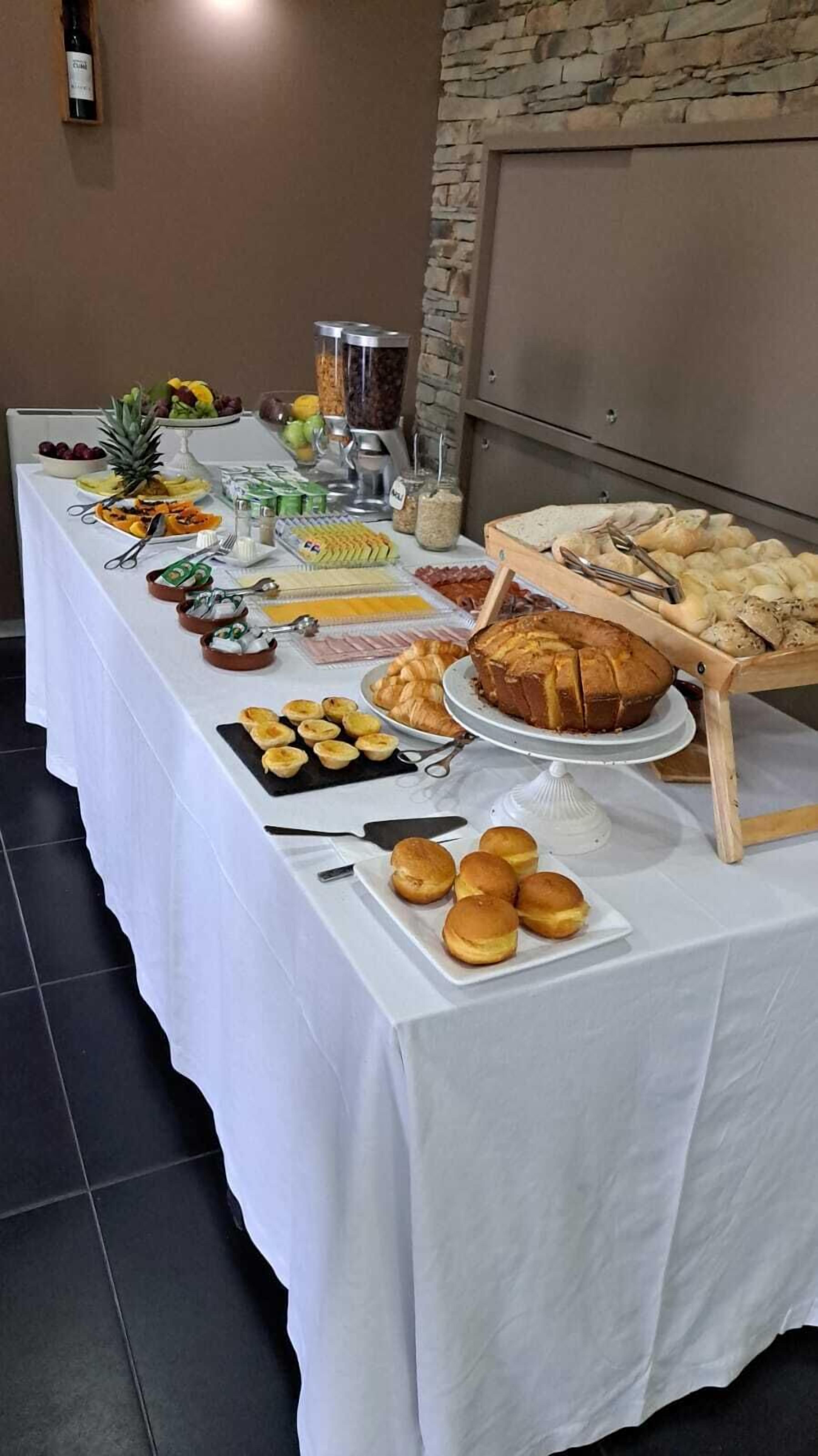 Un tavolo da buffet con diversi cibi, tra cui frutta, pasticcini e pane.