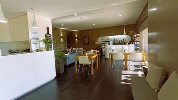 Una cocina moderna con una isla central, un rincón comedor con sofá y una barra equipada con refrigerador y botellas de vino.