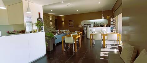 Une cuisine moderne dotée d’un îlot central, d’un coin repas avec un canapé et d’un bar équipé d’un réfrigérateur et de bouteilles de vin.