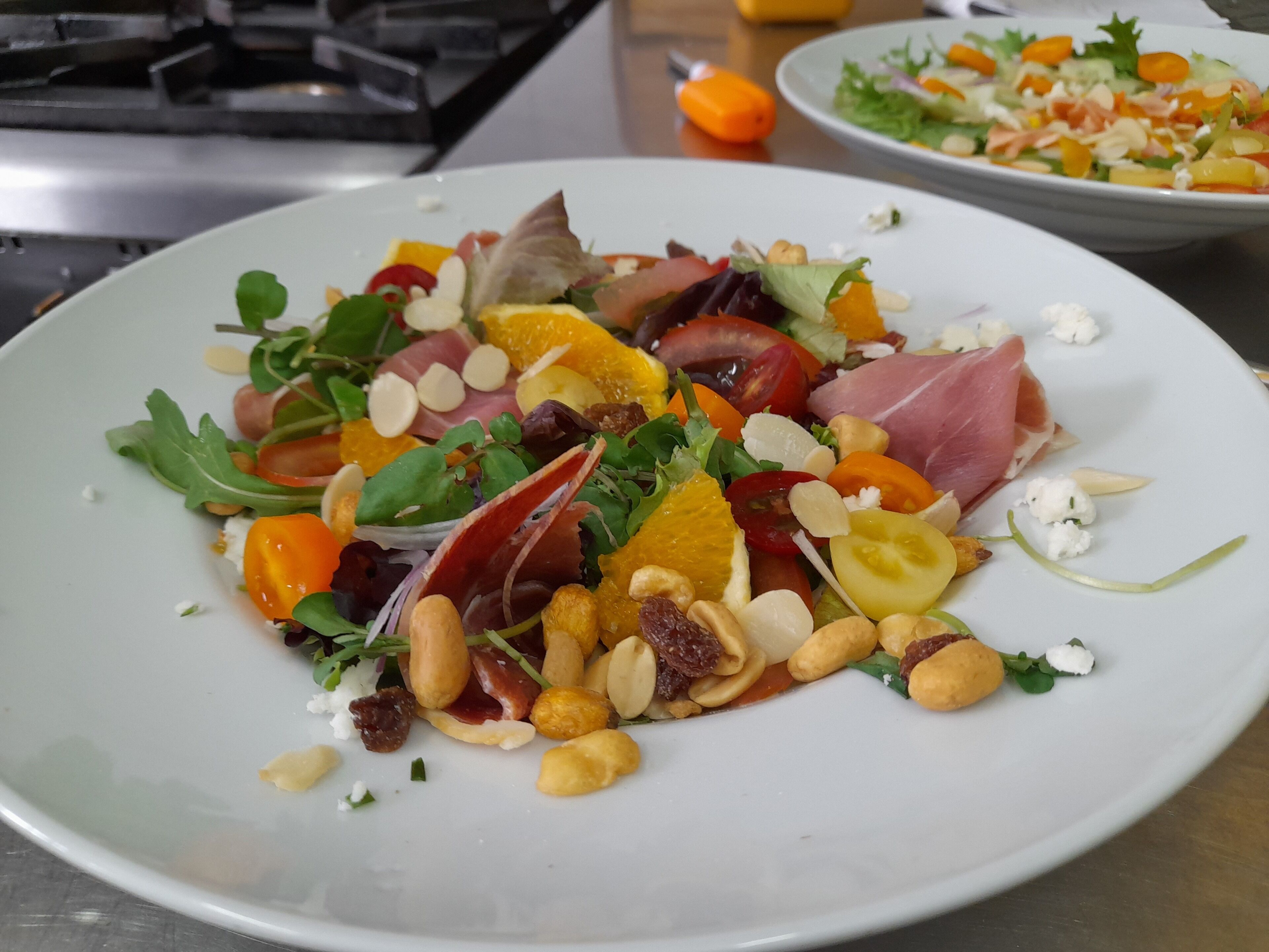 Un piatto di insalata mista con verdure, noci e carni varie.