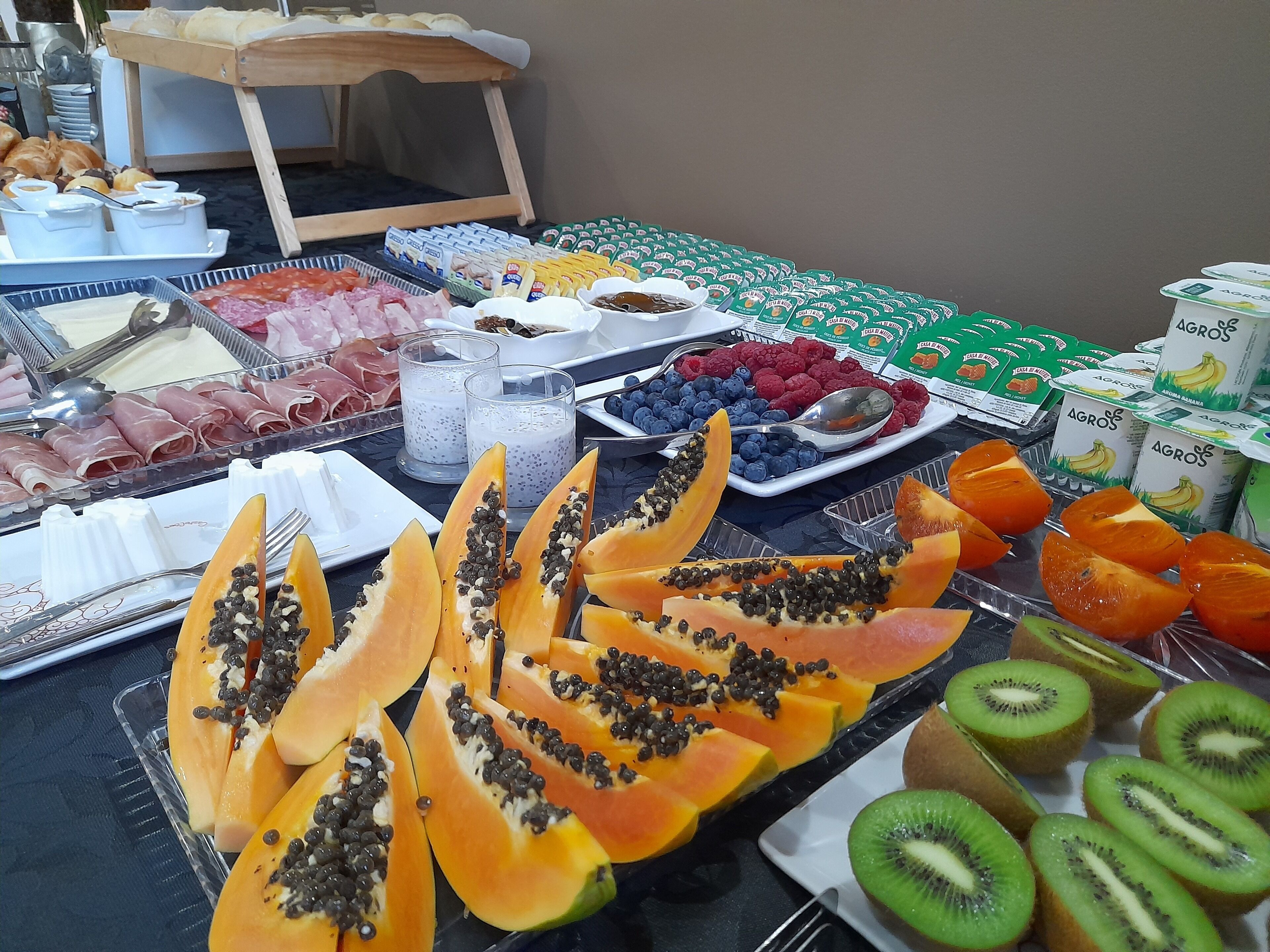 A buffet with various food items including meats, fruits, and dairy products.