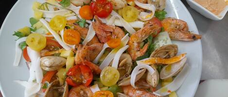 Ein Teller mit Meeresfrüchtesalat, darunter Garnelen, Muscheln und Kirschtomaten.