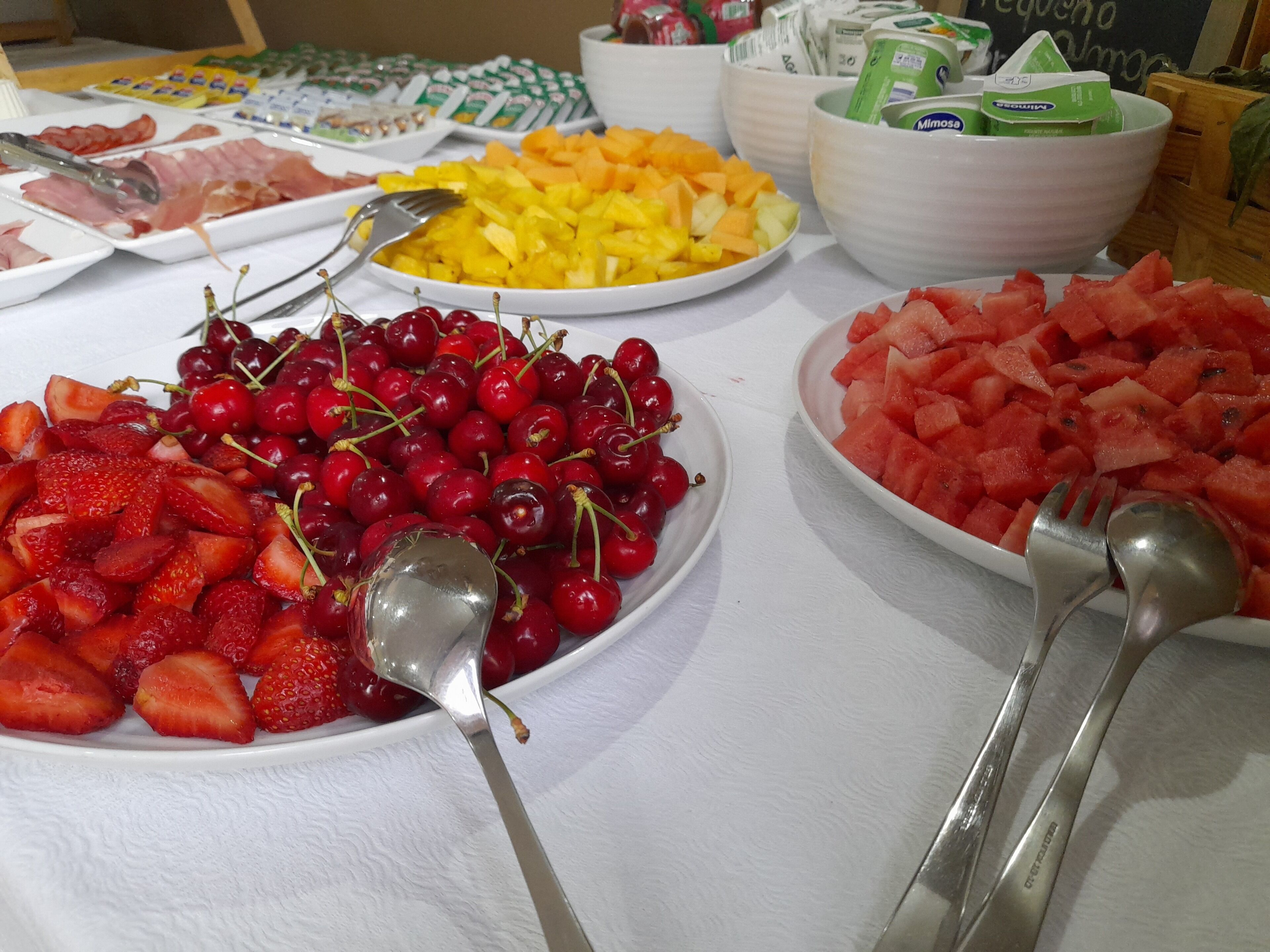 Une table de buffet garnie de divers fruits et un saladier de mimosas.