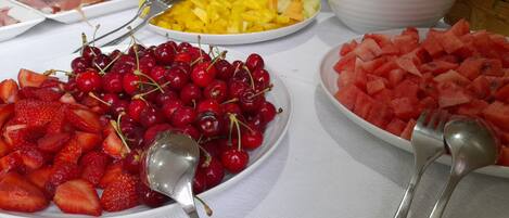 Une table de buffet garnie de divers fruits et un saladier de mimosas.