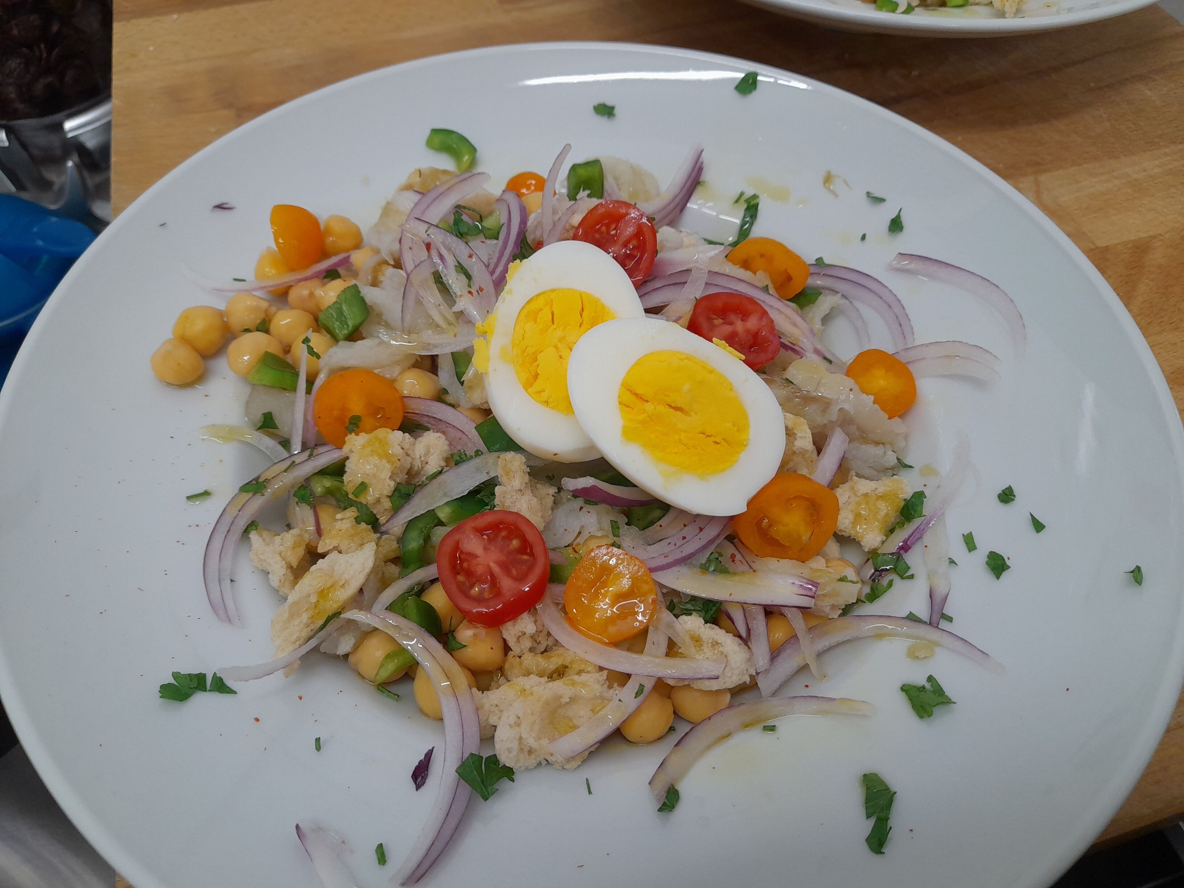 A plate of salad with chickpeas, tomatoes, onions, and boiled eggs.