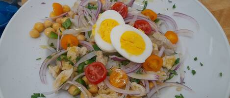 A plate of salad with chickpeas, tomatoes, onions, and boiled eggs.