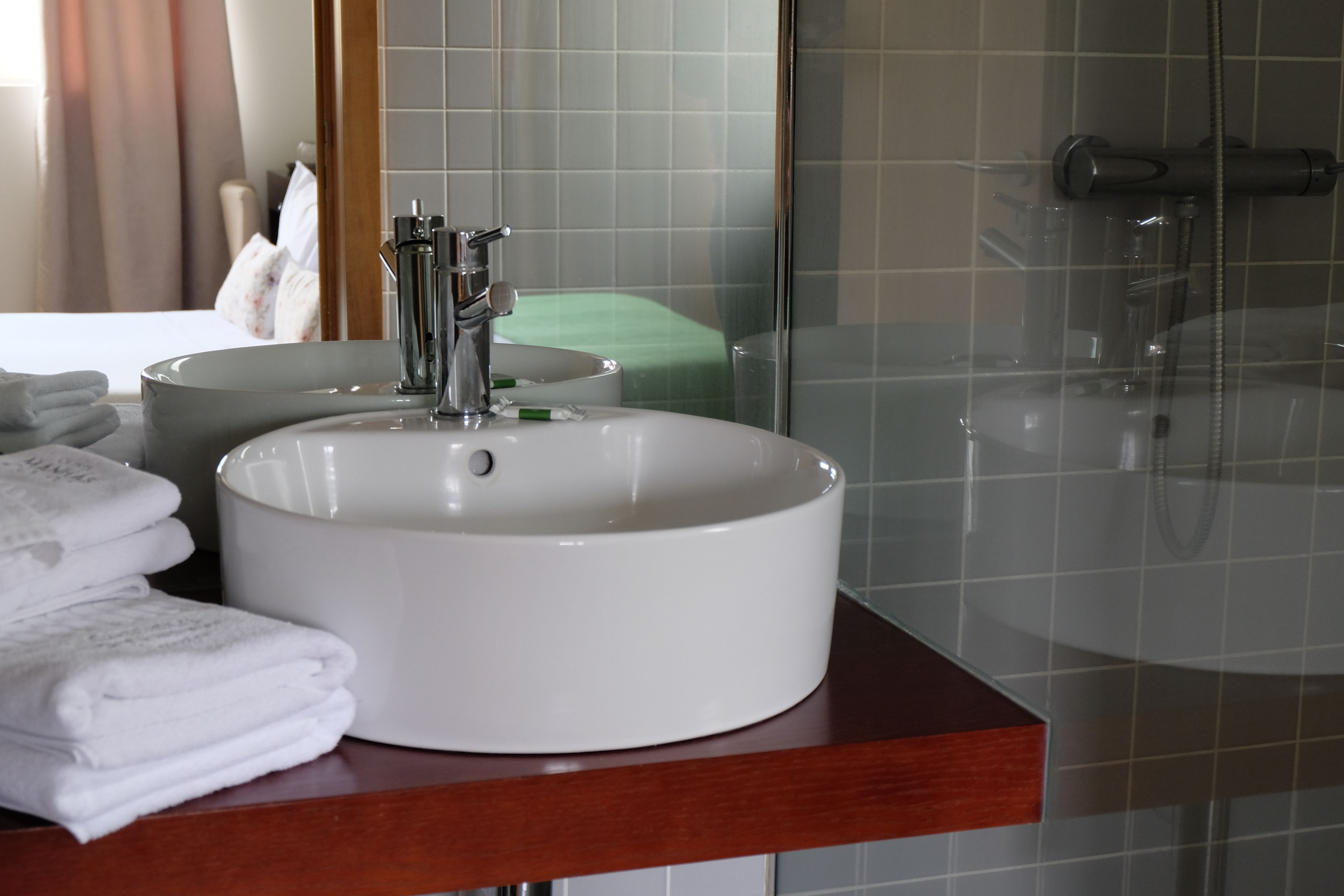 Un baño con un lavamanos blanco, un espejo y una ducha.