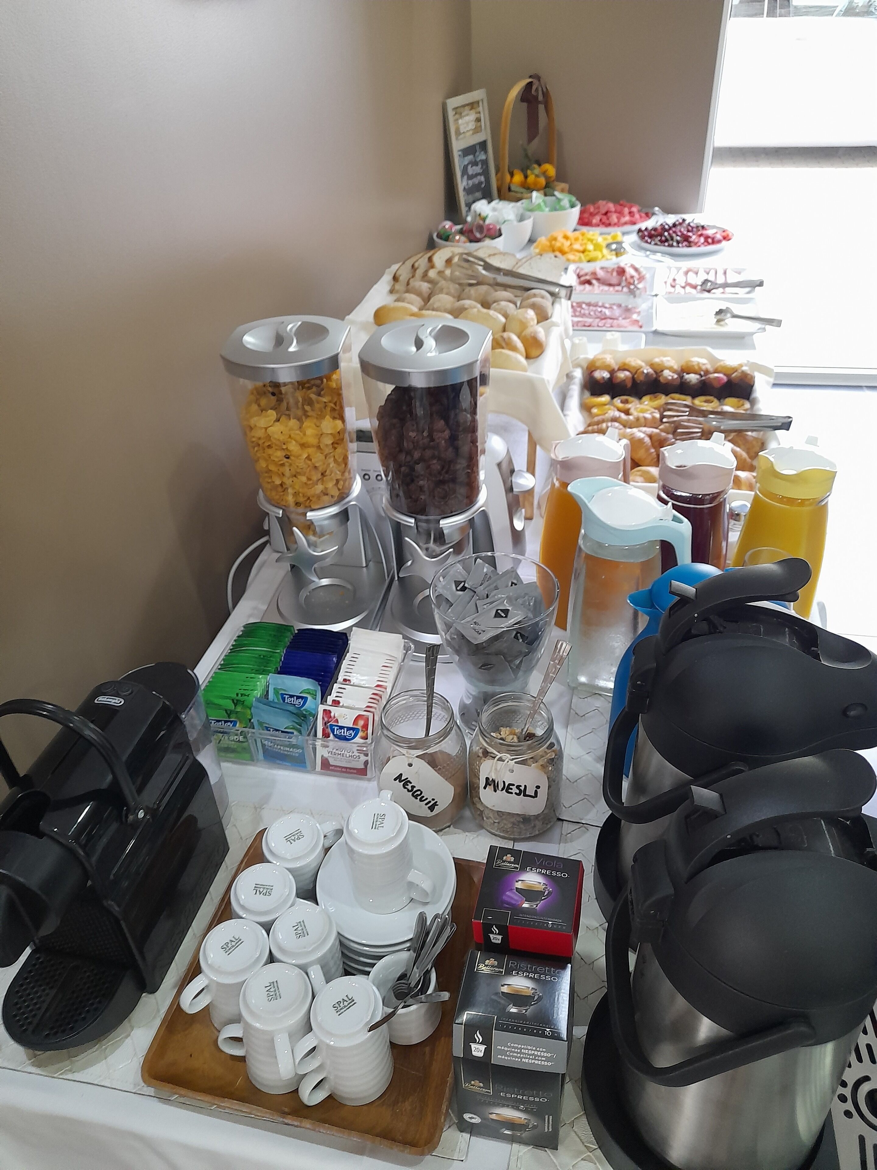 Una mesa de buffet con diversos alimentos, salsas y equipo para preparar café.