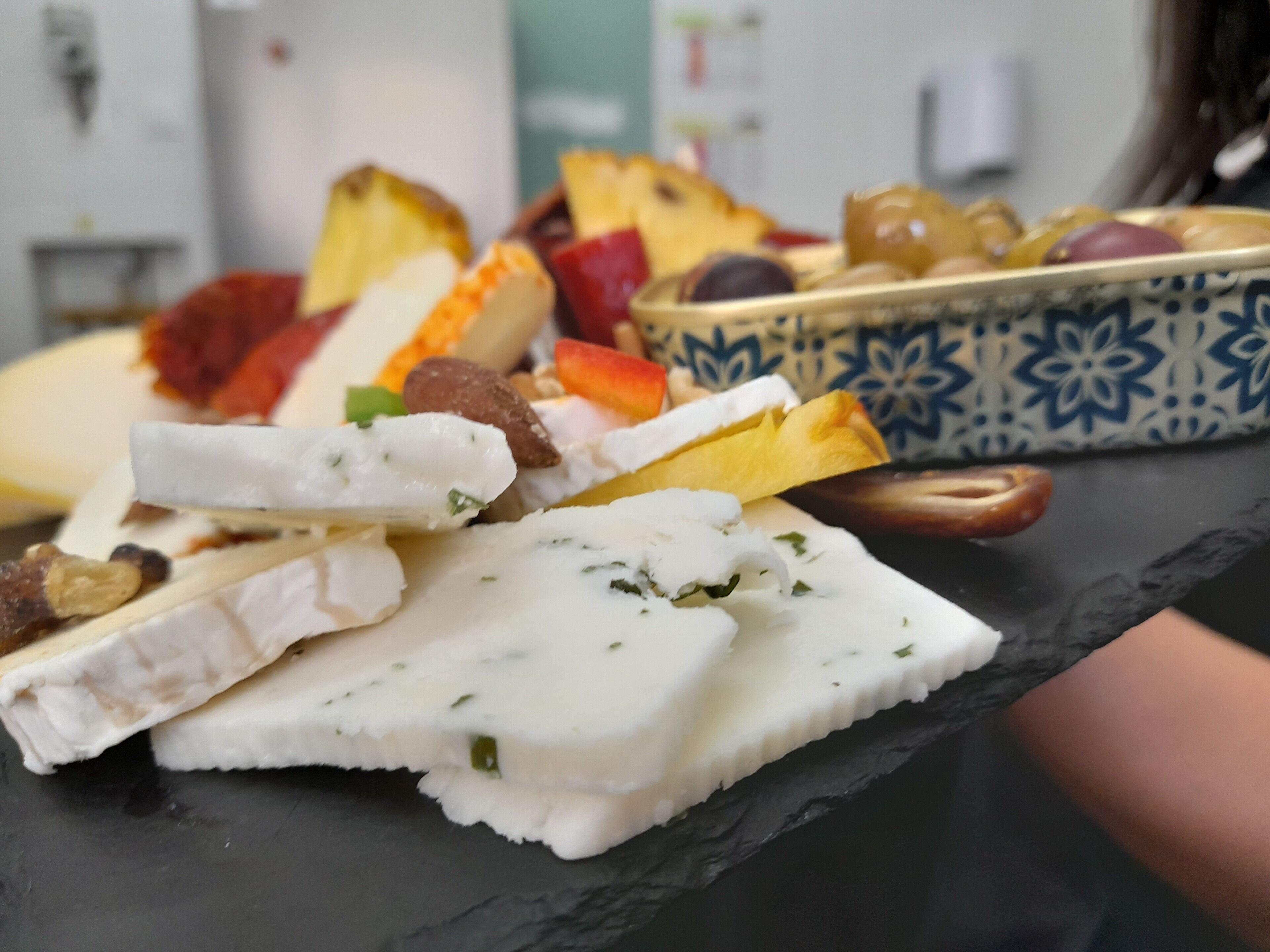 Une sélection de fromages et de fruits présentés sur une planche d’ardoise.