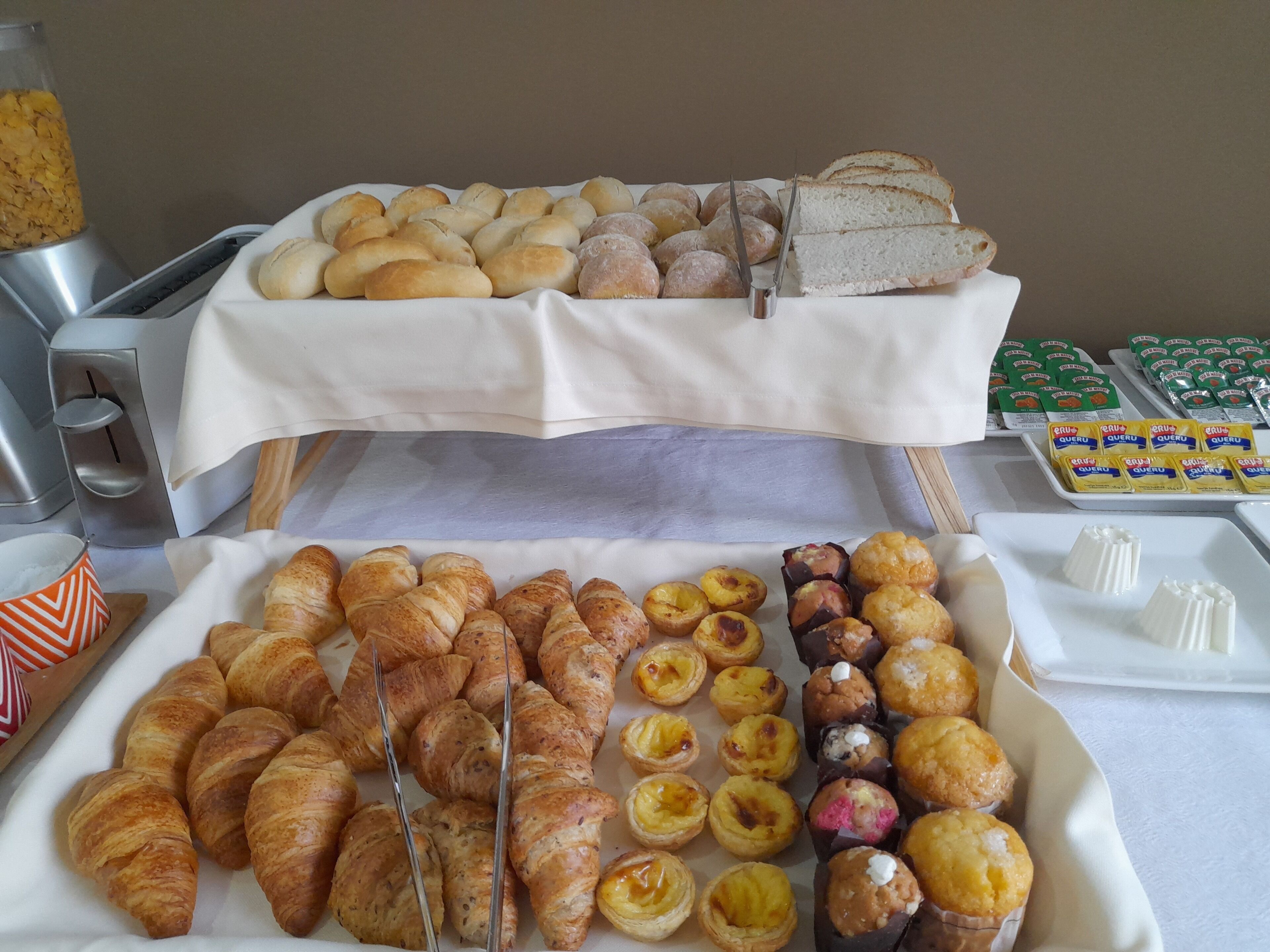 A buffet with various baked goods including croissants, bread rolls, and pastries.