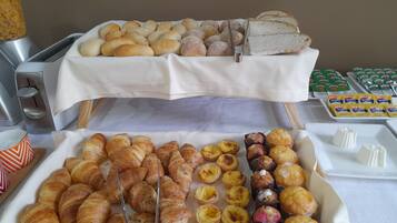 A buffet with various baked goods including croissants, bread rolls, and pastries.