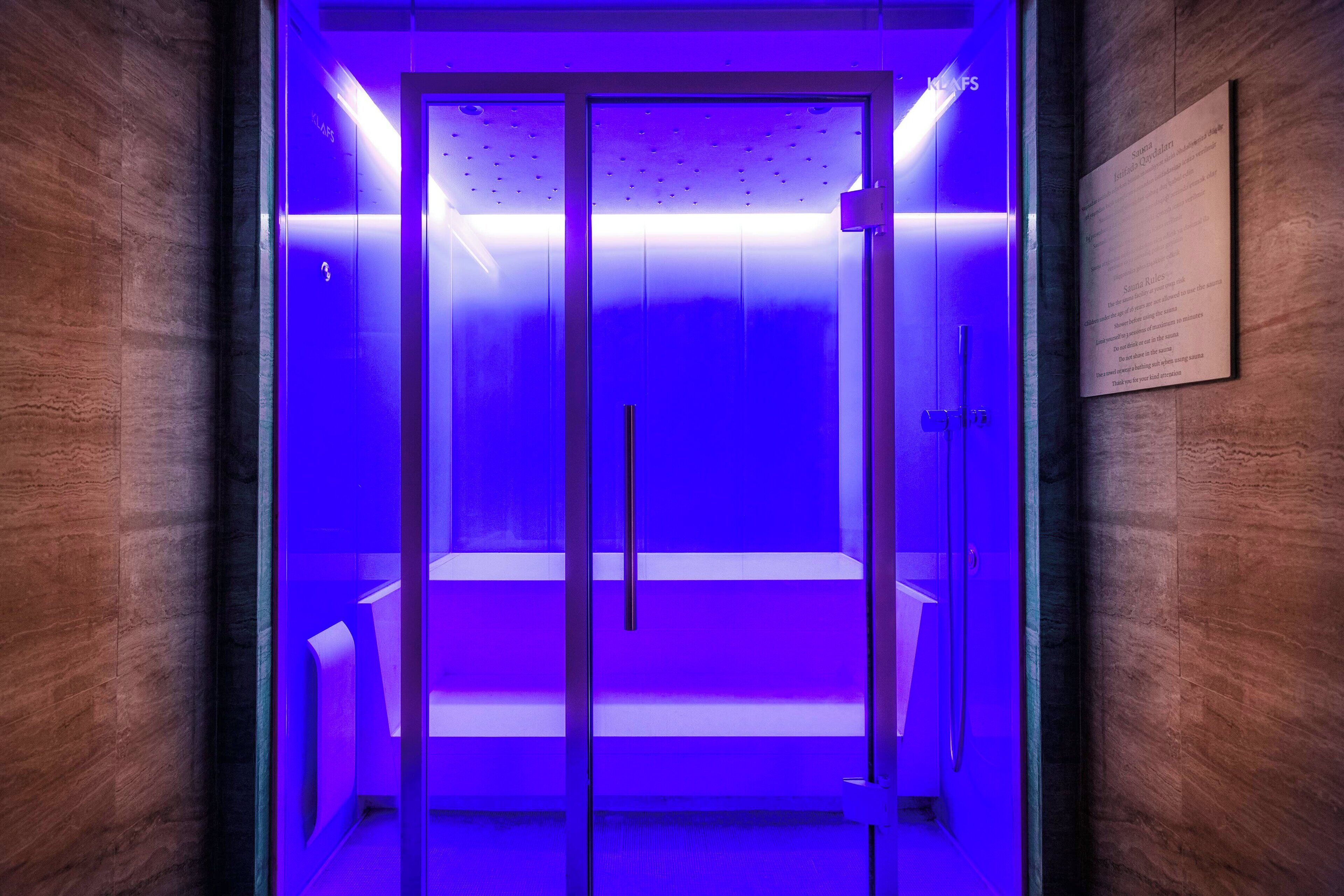 A modern elevator with a glass door and a blue light.