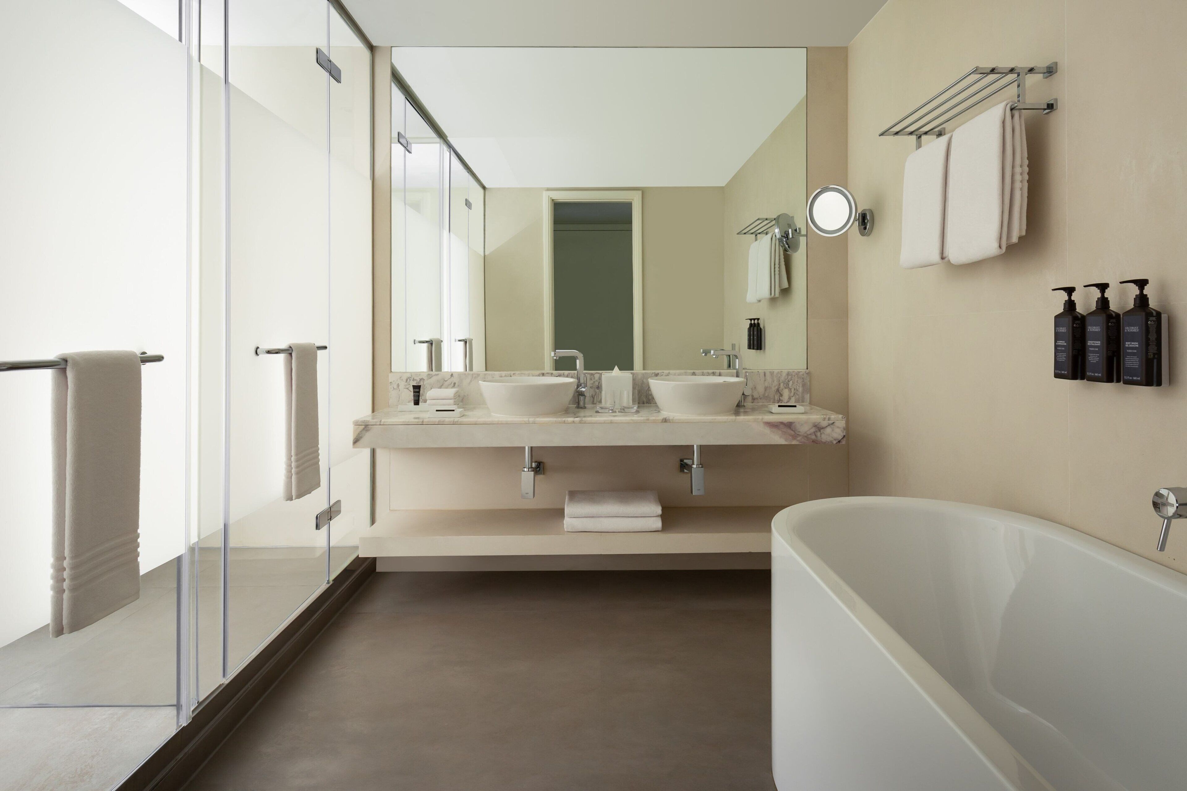 A modern bathroom with a glass shower enclosure, a freestanding bathtub, and a double vanity with two sinks.