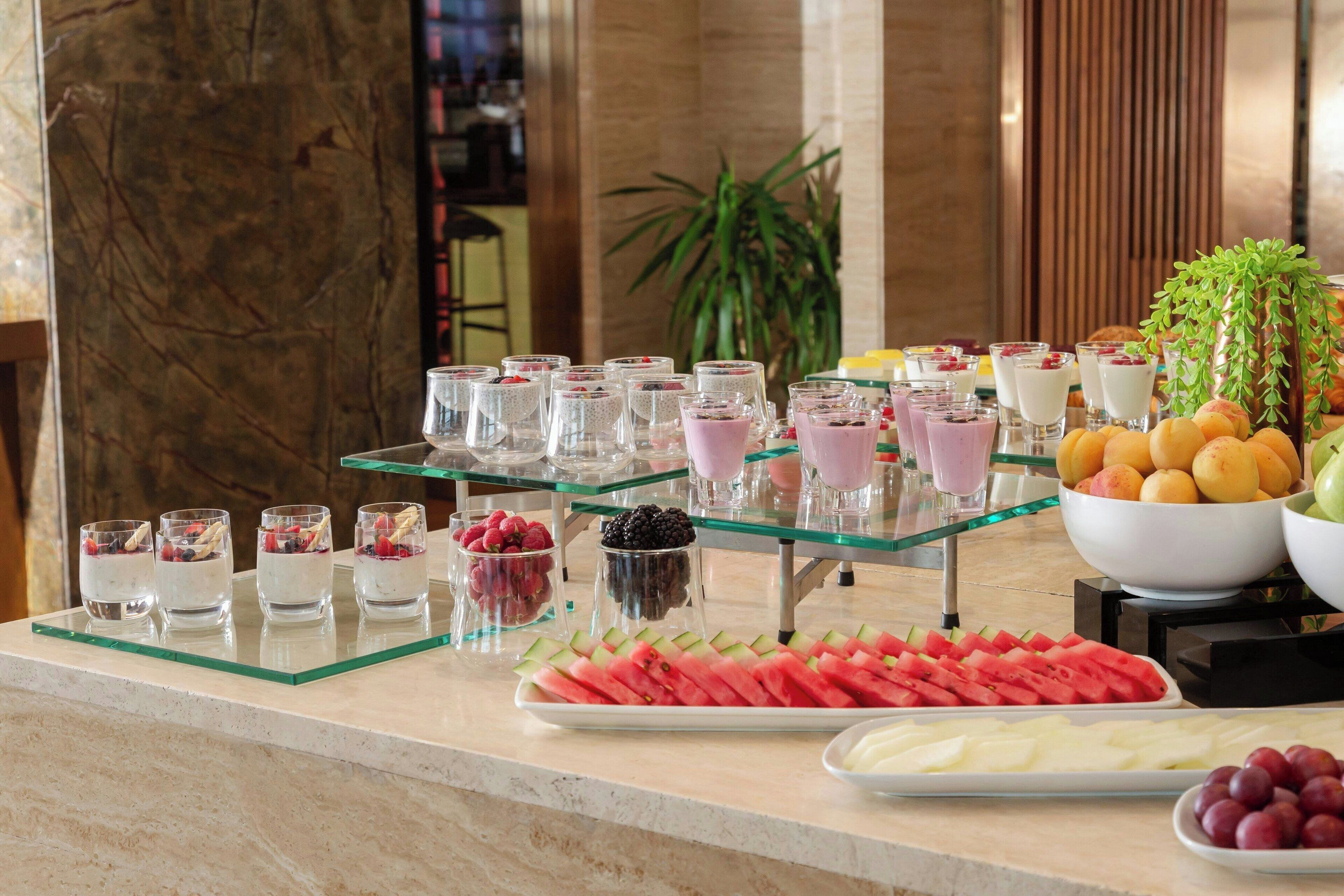 A buffet with various food items including fruits, desserts, and beverages.
