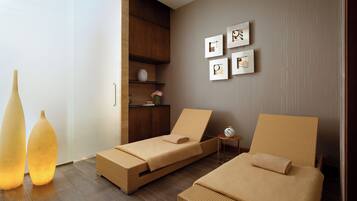 A modern hotel room with two single beds, a wooden wardrobe, a small side table, and wall-mounted artwork.