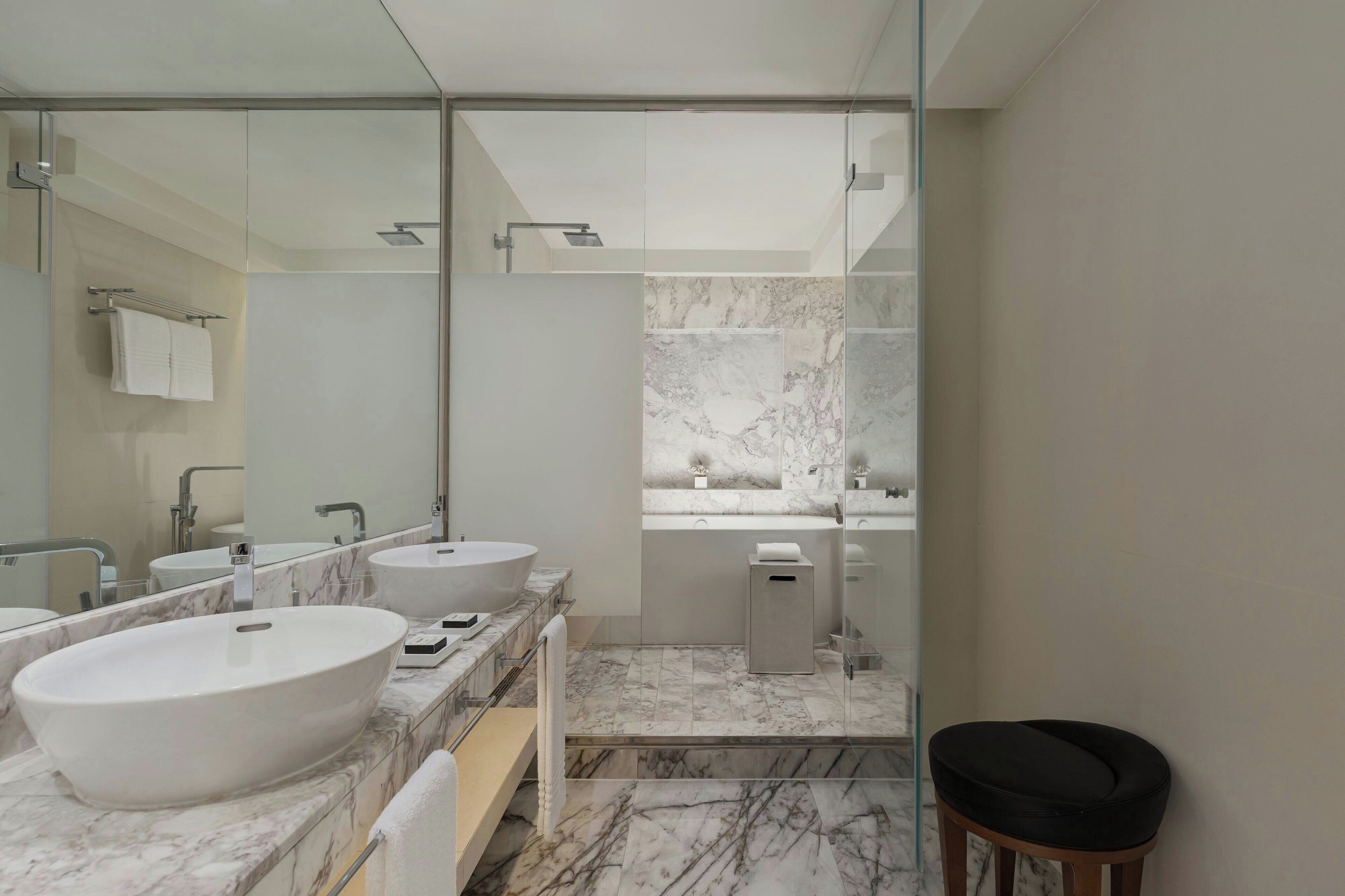 A modern bathroom with a large mirror, two sinks, and a shower area.