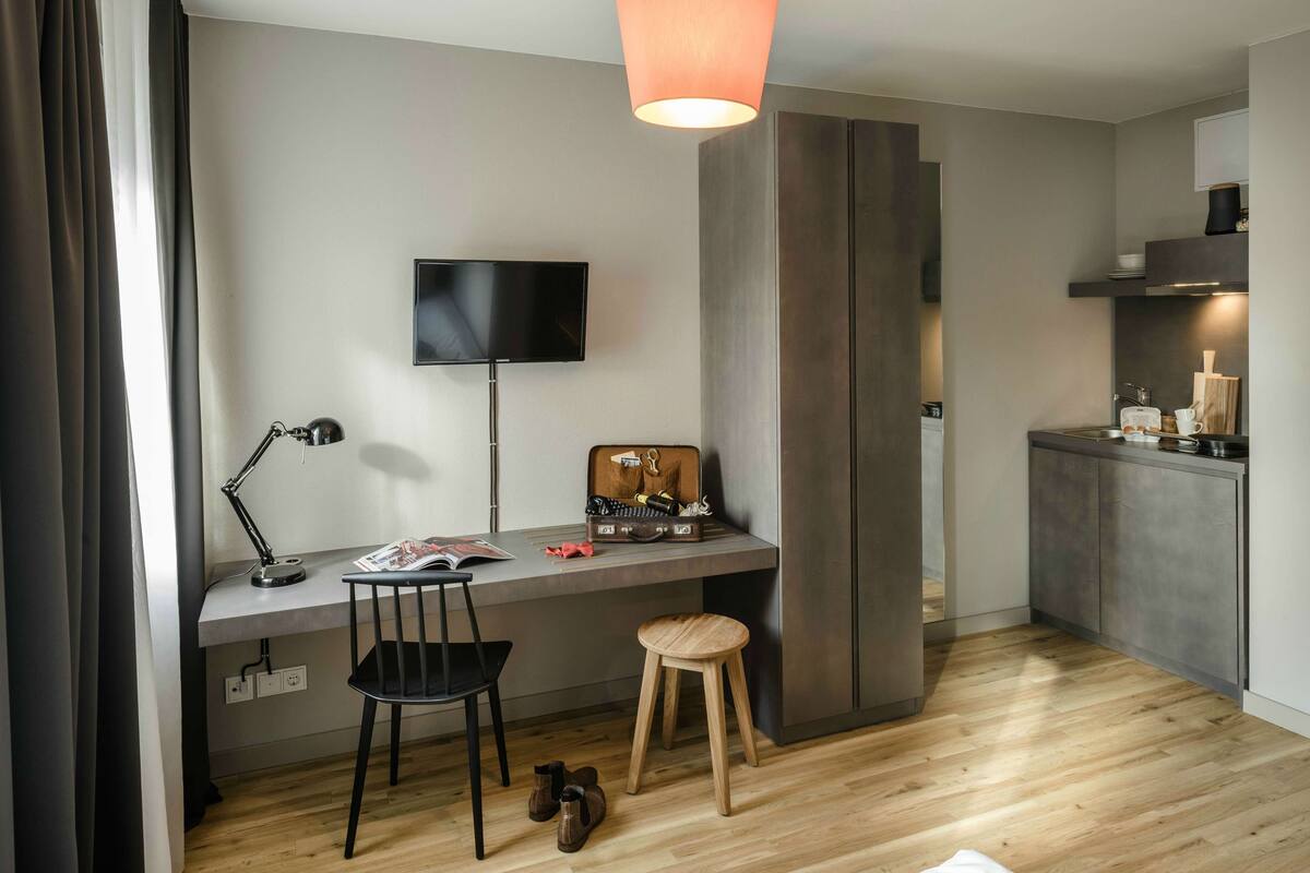 A modern kitchen with a built-in stove, a dining area with a table and chairs, and a TV mounted on the wall.
