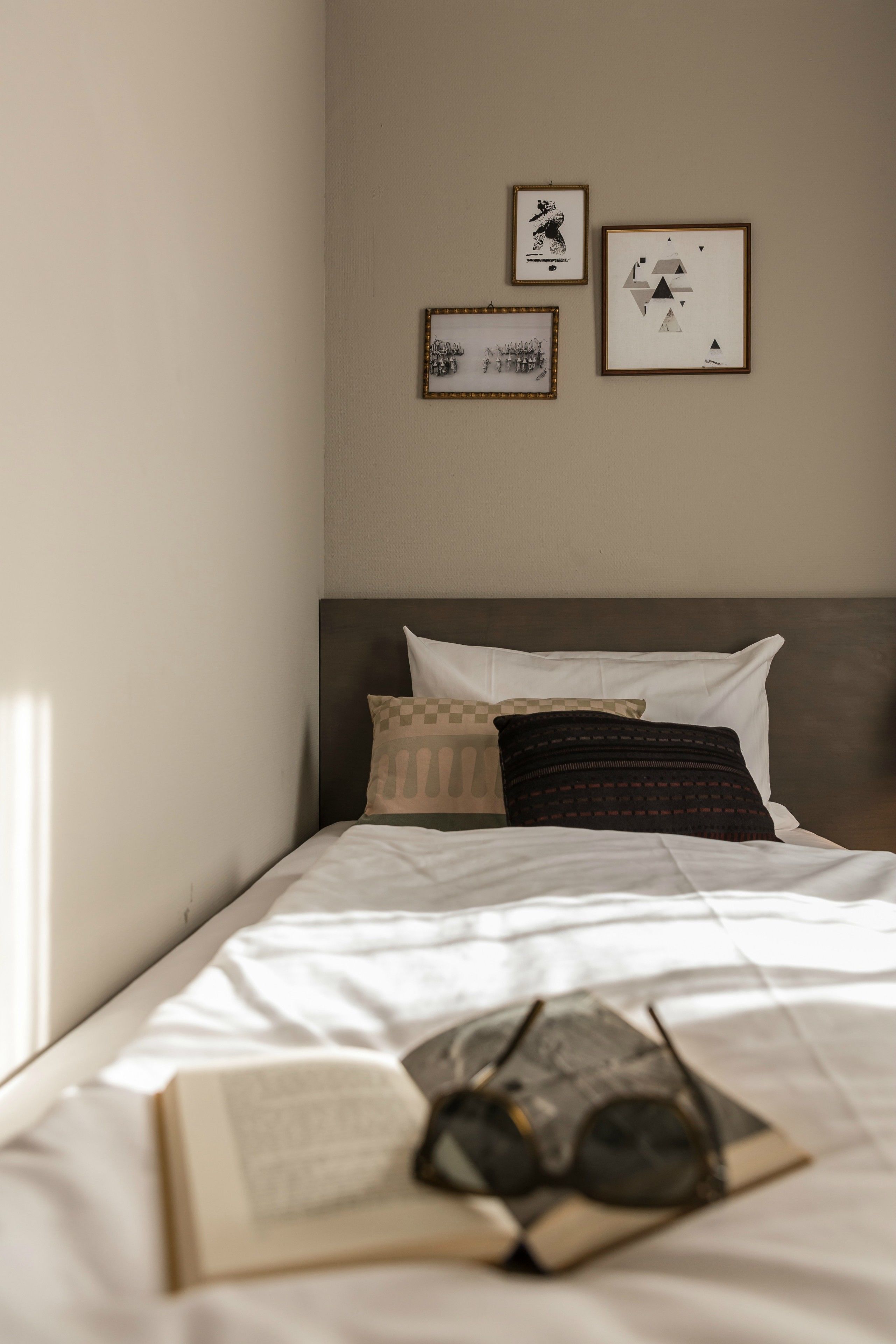 A neatly made bed with pillows, a framed picture, and a book on it.