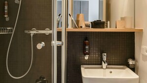 Un baño moderno con cabina de ducha de vidrio, una bañera blanca, un lavabo con taburete de madera y un espejo sobre el lavabo.