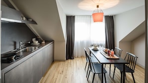 Una cocina moderna con comedor, que presenta piso de madera, armarios oscuros y una mesa de comedor con sillas.