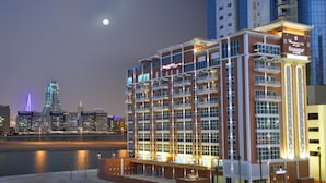 Un hotel de varios pisos con balcones y vista al horizonte urbano de noche.