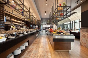 Un espace buffet comprenant plusieurs stands de restauration, un long comptoir avec des assiettes et une grande variété de plats.