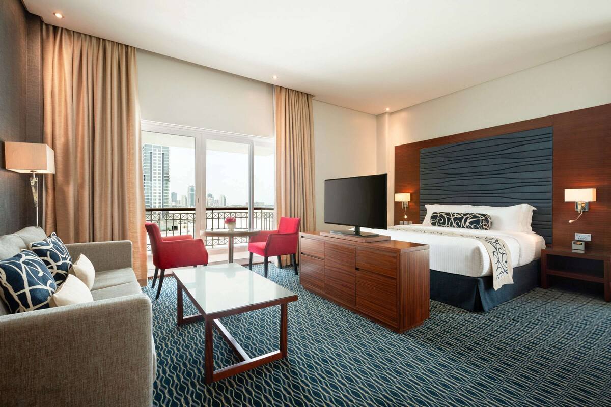Une chambre d’hôtel équipée d’un lit, d’une télévision, d’un bureau, d’une chaise et d’un canapé.
