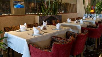 Un restaurante con mesas dispuestas para comer, con sillas tapizadas en rojo y un salpicadero de azulejos.