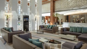 Eine geräumige Lobby mit mehreren Sitzbereichen, einem Empfangstresen und dekorativen Wandverkleidungen.