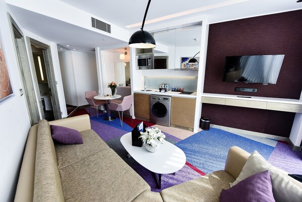 Una habitación de hotel moderna con un sofá, una mesa de centro y un televisor de pantalla plana.