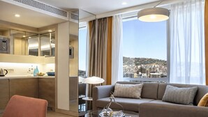 A modern hotel room with a sofa, a glass coffee table, a dining area, and a view of a cityscape. - Tango Arjaan by Rotana Istanbul (Istanbul)