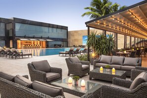 A modern outdoor lounge area with wicker furniture, a pool, and a bar. - Tango Arjaan by Rotana Istanbul (Istanbul)