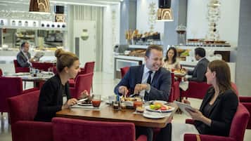 A modern dining area with red upholstered chairs, a wooden table, and a variety of breakfast items.