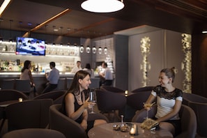 A modern bar area with round tables, bar stools, and a television screen. - Tango Arjaan by Rotana Istanbul (Istanbul)