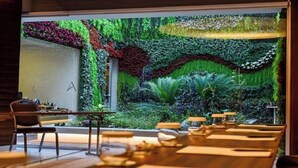 A restaurant with a large window overlooking a lush indoor garden. - Tango Arjaan by Rotana Istanbul (Istanbul)